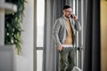 Happy businessman talking on smart phone while looking through window at office Royalty Free Stock Photo