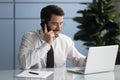 Happy businessman talking on smartphone looking at laptop screen. Royalty Free Stock Photo