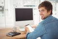 Happy businessman using digital tablet while sitting at desk Royalty Free Stock Photo