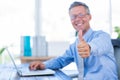 Happy businessman using laptop computer and looking at camera with thumbs up Royalty Free Stock Photo