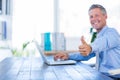 Happy businessman using laptop computer and looking at camera with thumbs up Royalty Free Stock Photo