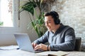 Happy businessman wearing headphones singing song at workplace, funny employee or freelancer using laptop, enjoying favorite track