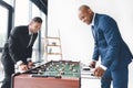 Happy businessmen playing table football together