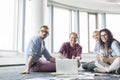 Happy businesspeople looking away while working on floor at creative office Royalty Free Stock Photo