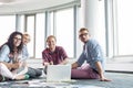 Happy businesspeople looking away while working on floor at creative office Royalty Free Stock Photo