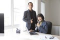 Businesswoman and businessman showing thumbs up sign with computer on wooden table in office background. Royalty Free Stock Photo