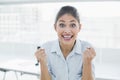 Happy businesswoman clenching fists in office Royalty Free Stock Photo