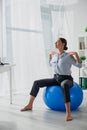 Happy businesswoman exercising on fitness balls in office