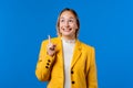 Happy businesswoman having idea eureka moment, pointing finger up on blue Royalty Free Stock Photo