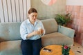 Happy young businesswoman holding a cup sitting on a sofa at home. 30s woman in glasses in a cafe drinking coffee Royalty Free Stock Photo