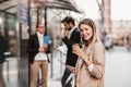 Happy businesswoman holding digital tablet and coffee to go outside of modern building, businesspeople in background Royalty Free Stock Photo