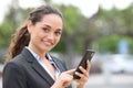 Happy businesswoman holds phone and looks at you