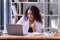 Happy businesswoman laughing with joy at the good news about work at the workplace, gladly looking at laptop screen, feeling