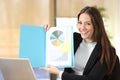 Happy businesswoman showing blank document at camera