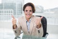 Happy businesswoman showing thumbs up at her desk Royalty Free Stock Photo