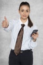 Happy businesswoman shows thumb up, phone in hand