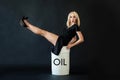 Happy businesswoman sitting on crude oil barrel on black background. Crude oil and petroleum industry concept