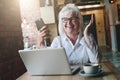 Happy businesswoman sitting at table in front of laptop, holding Royalty Free Stock Photo