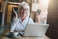 Happy businesswoman sitting at table in front of laptop, holding Royalty Free Stock Photo