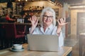 Happy businesswoman sitting at table in front of laptop, holding hands up and smiling, working, learning. Royalty Free Stock Photo