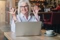 Happy businesswoman sitting at table in front of laptop, holding hands up and smiling, working, learning Royalty Free Stock Photo