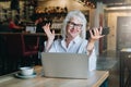 Happy businesswoman sitting at table in front of laptop, holding hands up and smiling, working, learning. Royalty Free Stock Photo