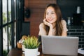 businesswoman smiling sitting alone at cafe desk with laptop computer she looking out of window Royalty Free Stock Photo