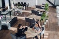 Happy businesswoman talking to businesswoman in office. Two women sitting at table with laptops and working.