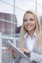 Happy businesswoman using digital tablet while looking away against office building Royalty Free Stock Photo