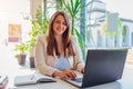 Happy businesswoman working online in office using laptop. Smiling middle-aged woman looking at camera sitting at desk Royalty Free Stock Photo