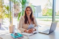 Happy businesswoman working online in office using laptop. Smiling middle-aged woman looking at camera sitting at desk Royalty Free Stock Photo