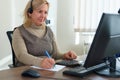 Happy businesswoman working using a calculator in a desk at office. She is using calculator and writing numbers down