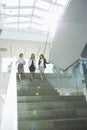 Happy businesswomen conversing while moving down steps in office