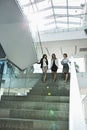 Happy businesswomen conversing while moving down steps in office