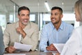 Happy busy business people working together talking at meeting table.