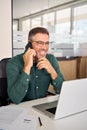 Happy busy mature business man making phone call using laptop in office. Royalty Free Stock Photo