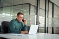 Happy busy older business man making phone call using laptop in office. Royalty Free Stock Photo