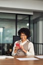 Happy busy young African business woman using smartphone in office. Vertical