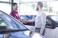 Happy buyer of new car shaking hands with dealer after transaction in the salon Royalty Free Stock Photo
