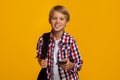 Happy calm caucasian teen boy pupil with backpack and smartphone ready to learn, chatting with friend