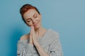 Happy calm redhead grateful woman holding hands in prayer gesture with closed eyes in studio Royalty Free Stock Photo