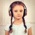 Happy calm serious kid girl in blue dress listening the music in