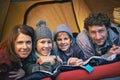 Happy campers. Portrait of smiling family of four relaxing inside their tent on a camping trip.