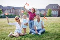 Happy Canada Day. Caucasian family with kids boy and girl sitting on ground grass in park and waving Canadian flags. Parents with