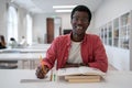 Happy carefree African American guy student with pencil sits at desk in university auditorium Royalty Free Stock Photo