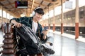 A carefree Asian man backpacker is listening to music while waiting for his train Royalty Free Stock Photo
