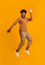 Happy carefree black man jumping over orange background