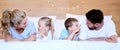 Happy carefree caucasian family lying cosy on bed while bonding together at home. Loving parents spending quality time Royalty Free Stock Photo