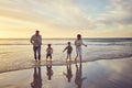 Happy and carefree family running and having fun on the beach at sunset. Mixed race parents and their kids spending time Royalty Free Stock Photo