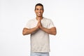 Happy, carefree handsome brazilian man in casual outfit, clasp hands together in pray, namaste gesture smiling joyfully